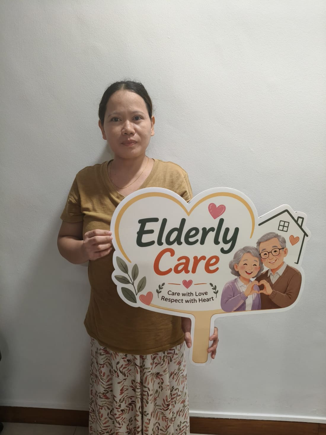 An Apex Maids helper holding an elderly care service placard